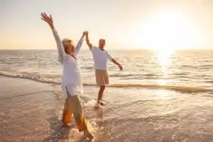 A couple walks arms-outstretched on the beach